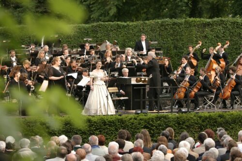 Operngala im Heckentheater 2006. Blick auf die Bühne mit Sängerinnen und Orchester in schwarz/weiß, umringt von grüner Bepflanzung.