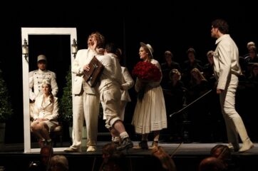 Die Sänger der Oper Der Vogelhändler auf der Bühne des Schlosstheaters, komplett in weiß gekleidet.